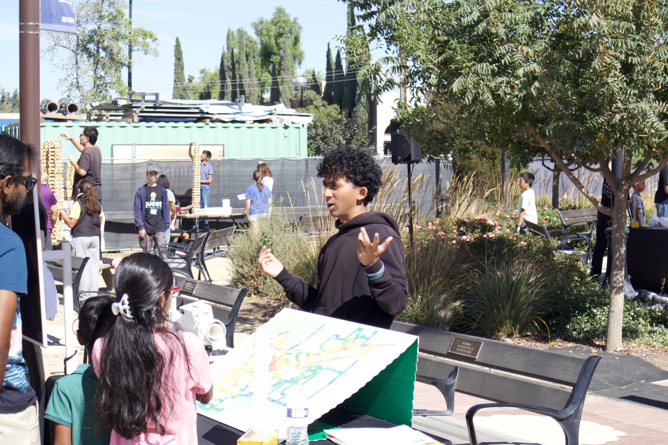 A student volunteer speaks with families at an outdoor foil-boat station.