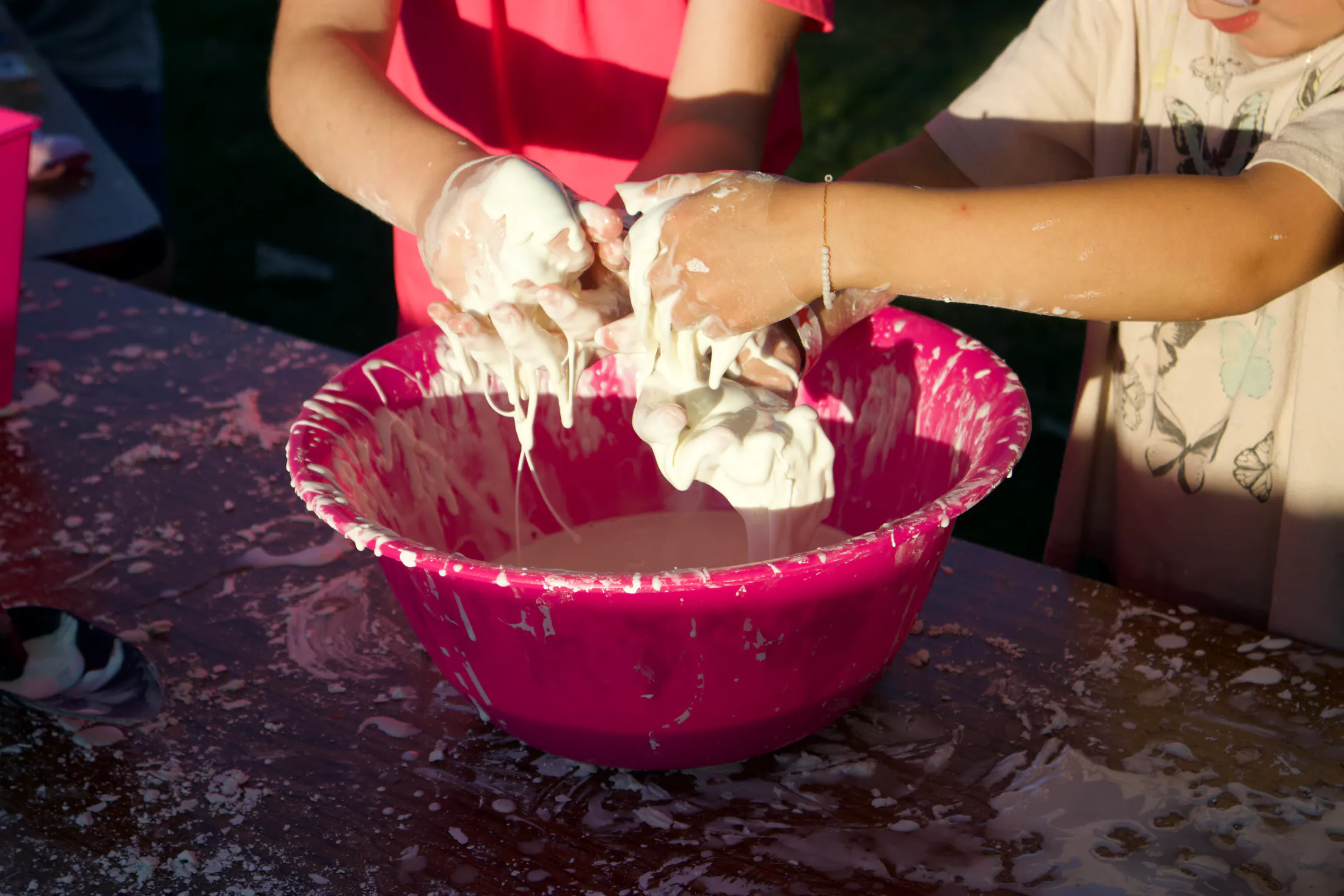 Young people and volunteers doing a hands-on activity outdoors at a community event.
